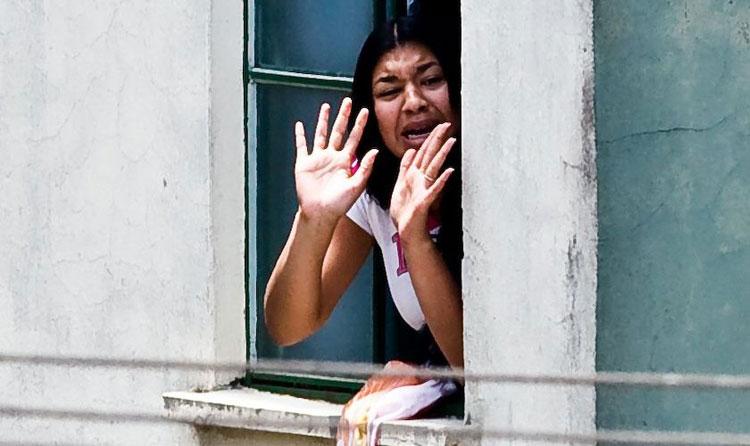 Foto de Eloá na janela de seu apartamento pedindo calma com as mãos