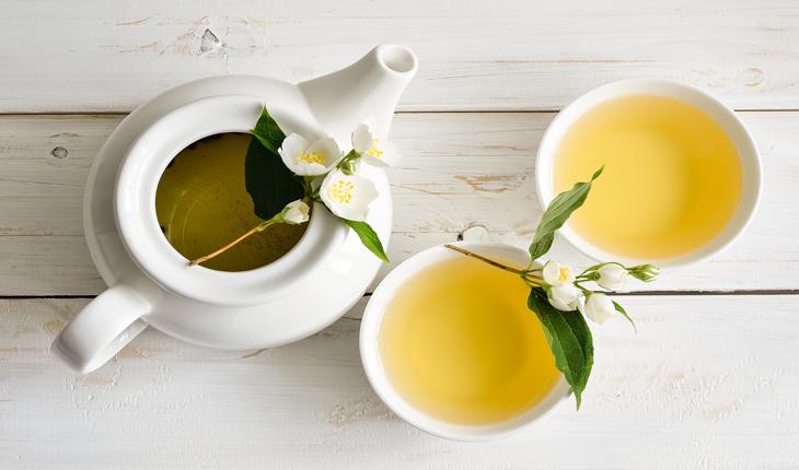 chá verde servido em um bule e duas xícaras decorado com flores brancos