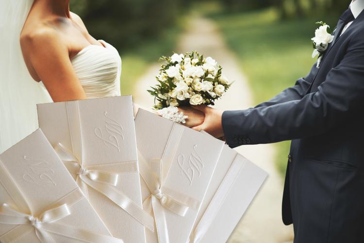 Casal segurando o buquê com os convites em primeiro planos (lista de casamento)
