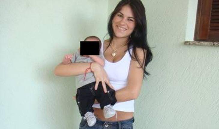 Foto de Eliza segurando o filho Brunino com uma parede verde atrás e uma tarja preta no rosto da criança