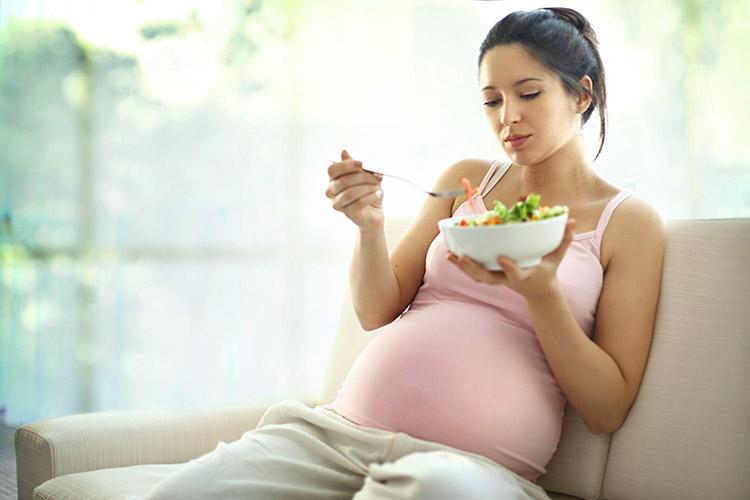 mulher gravida sentada comendo salada cansaco