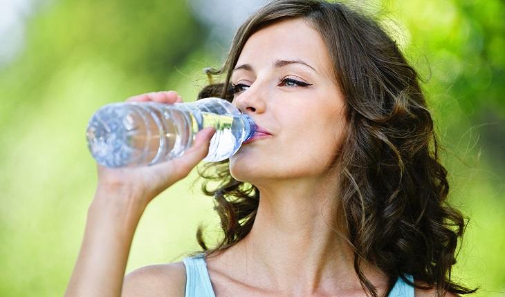 A foto mostra uma mulher bebendo uma garrafa de água com uma expressão tranquila no rosto. Manter-se hidratada é ´´otimo para sua capacidade de memória