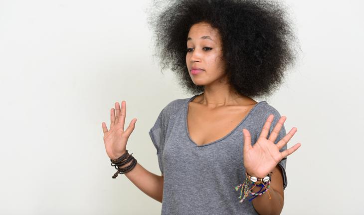 mulher negra com as mãos erguidas e o cabelo volumoso
