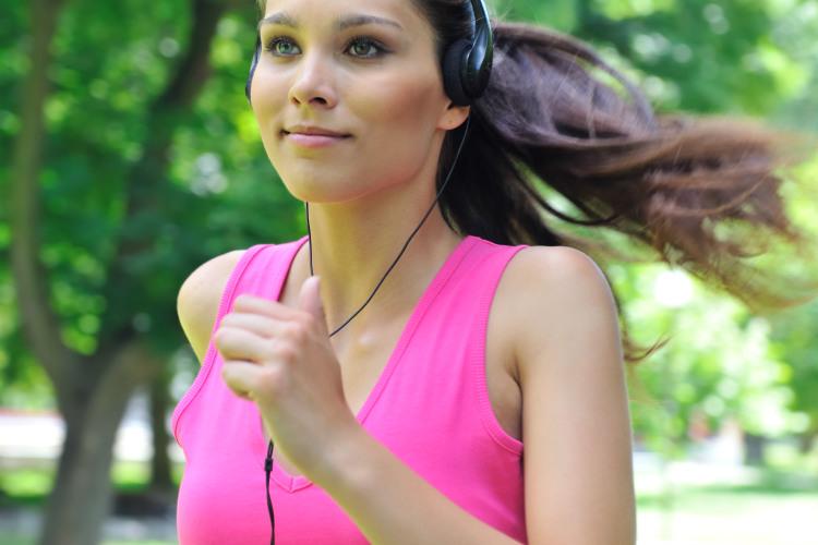 Mulher correndo com fone de ouvido músicas para treinar