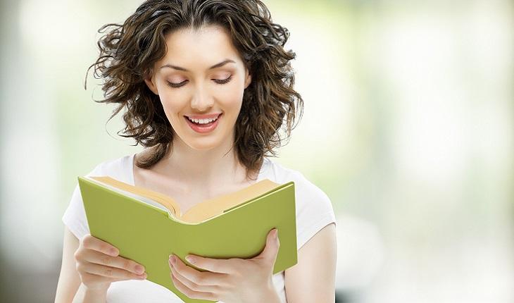 Na foto há uma mulher lendo um livro com capa verde. A leitura ajuda muito a desenvolver a capacidade de memória
