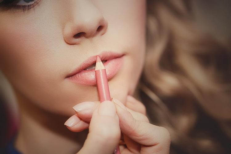 mulher passando um lápis na make, lábios rosados