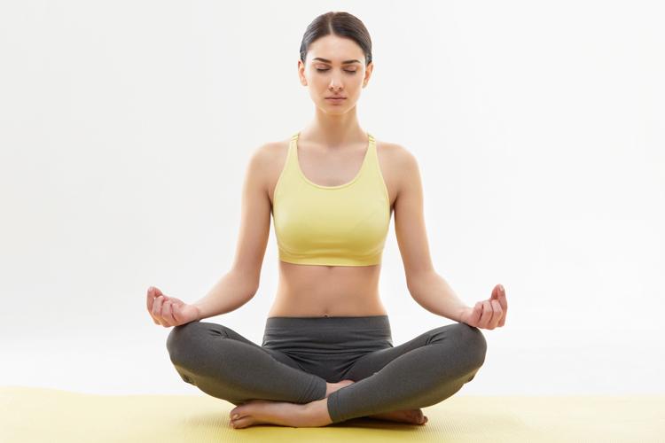 mulher sentada em posição de meditação praticando yoga contra artrite em casa