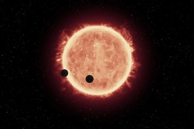 A ilustração mostra dois planetas do tamanho da Terra orbitando ao redor da estrela TRAPPIST-1
