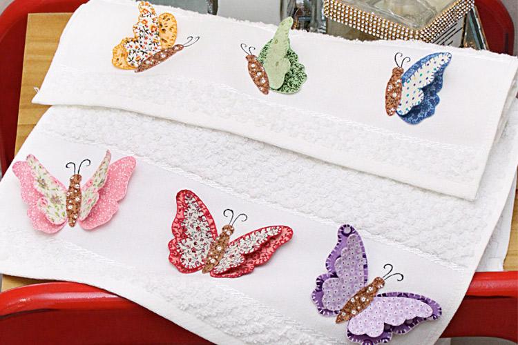 duas toalhas de lavabo com aplicações de borboletas em 3D decorando um banheiro