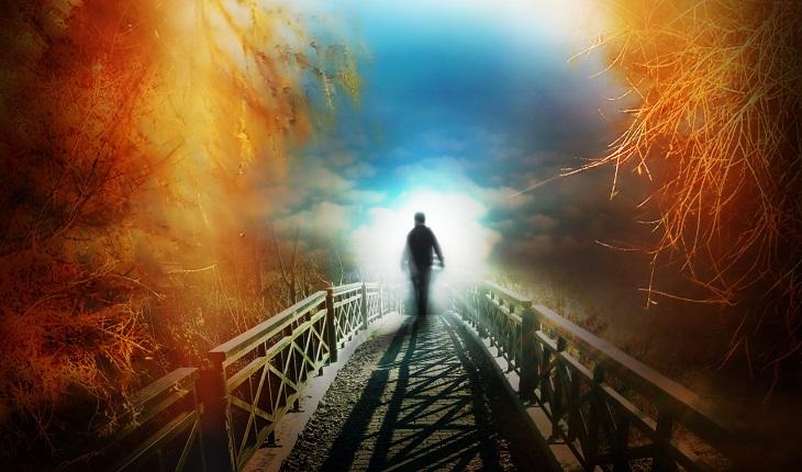 Na imagem há uma pessoa andando em direção a uma luz vinda do céu através de uma ponte, representando a morte no espiritismo