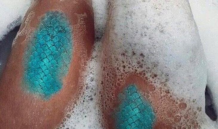 Imagem de uma tatuagem nas pernas de escamas de peixe na cor azul representando as escamas de uma cauda de sereia