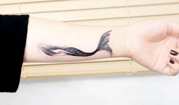 Imagem de tatuagem em preto e branco de uma sereia sem rosto nadando em traços finos