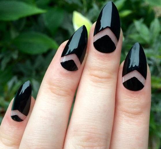 Mãos femininas mostram unhas feitas em material acrigel, na cor preta. As unhas tem detalhes desenhados em formato de seta, com esmalte vazado.