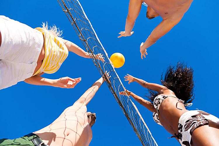 Quatro pessoas jogando vôlei de praia em um dia ensolarado