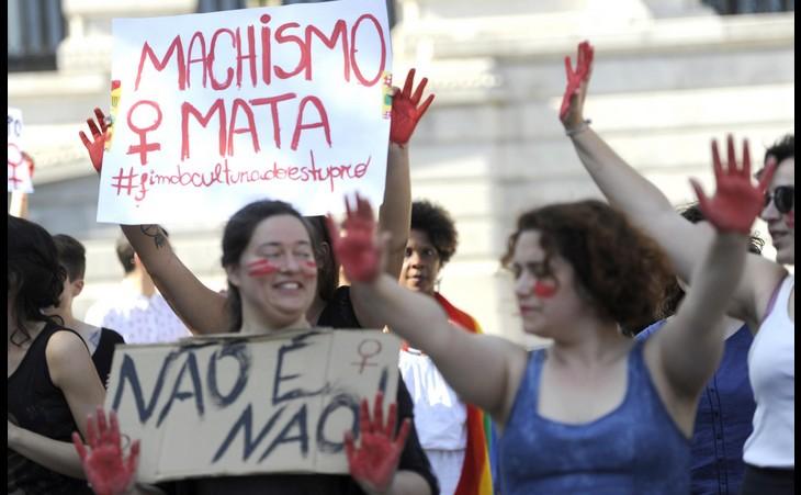 Mulheres portuguesas com expressões sérias e sorridentes seguram cartazes de protesto contra a violência