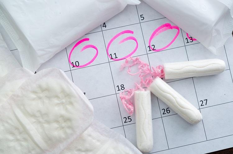 Imagem de absorventes internos, absorventes comuns e calendário com marcação circular com caneta cor-de-rosa