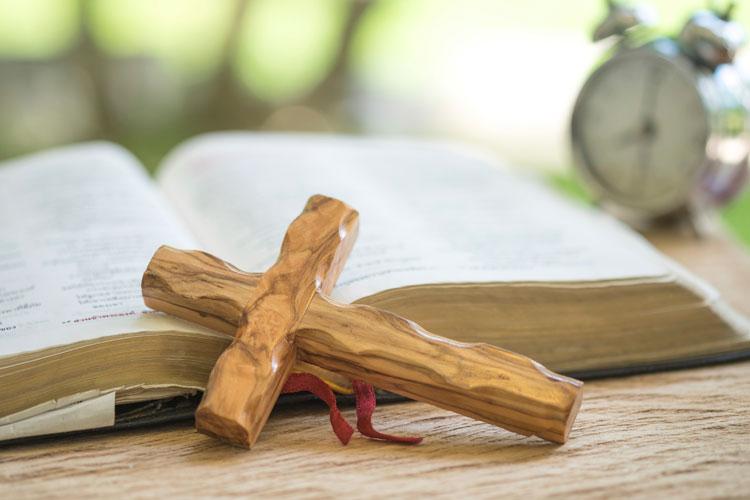 uma imagem de uma cruz de madeira encostada em uma bíblia. 
