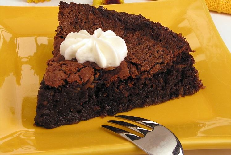 bolo de chocolate sem farinha em um prato amarelo com garfo ao lado