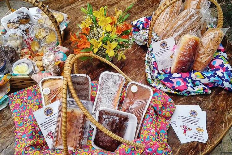 bolos, pães, flores e cestas sobre uma mesa de madeira, mulher cria negócio de sucesso