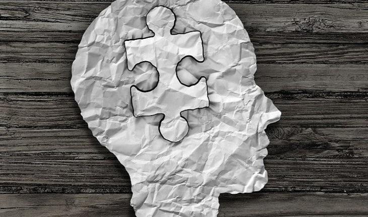 uma cabeça feita de papel e com uma peça de quebra-cabeça no lugar do cérebro