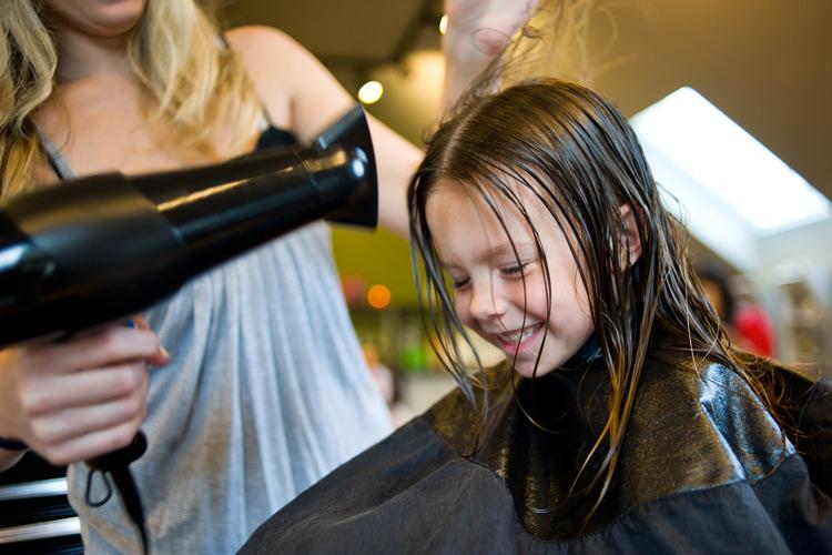 cabeleireira secando o cabelo de uma menina criança