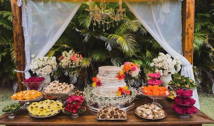 Mesa de bolo de casamento cheia de flores, comidas e bebidas