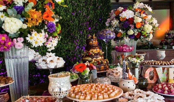 Mesa de bolo de casamento com flores laranjas e roxas em casamento no campo