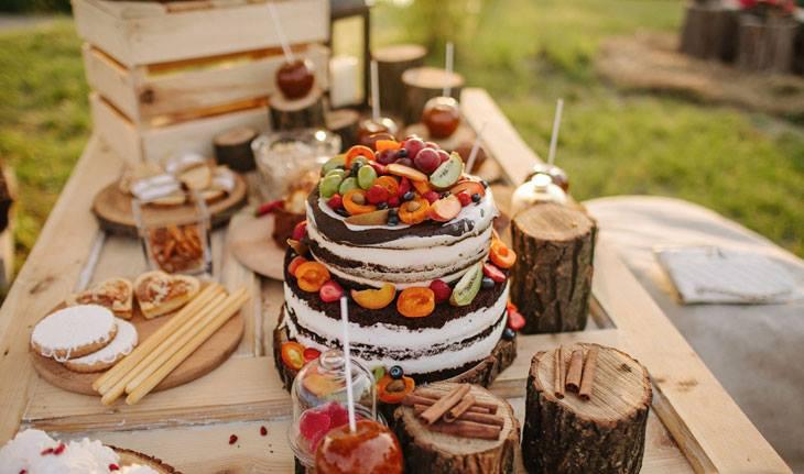 Casamento no campo: Mesa de bolo de casamento decorada com frutas e madeira