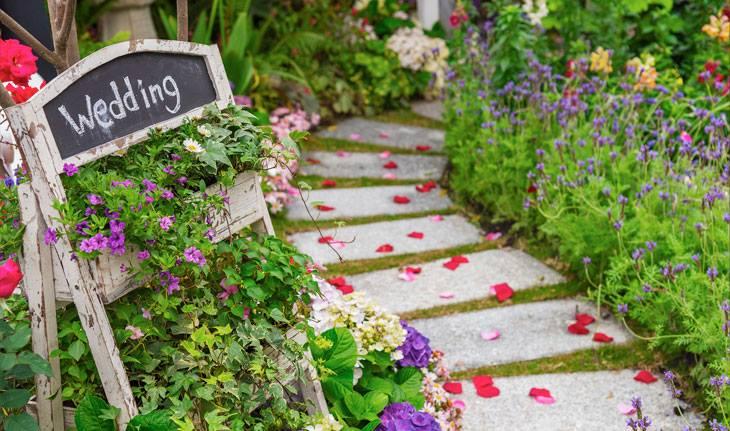 Caminho de pedras repleto de flores com placa ao lado indicando: casamento