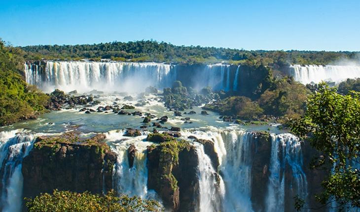 Vista das Cataratas de Foz do Iguaçu com água azul e pouca vegetação
