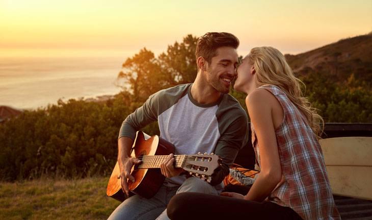 Homem tocando violão para a namorada ao ar livre