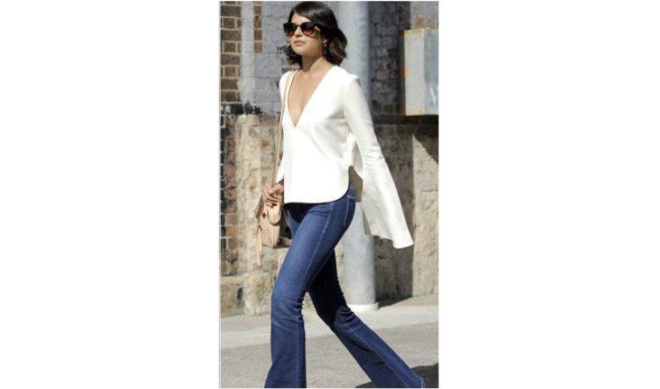 Na foto há uma mulher usando uma blusa branca com manga flare e calça jeans