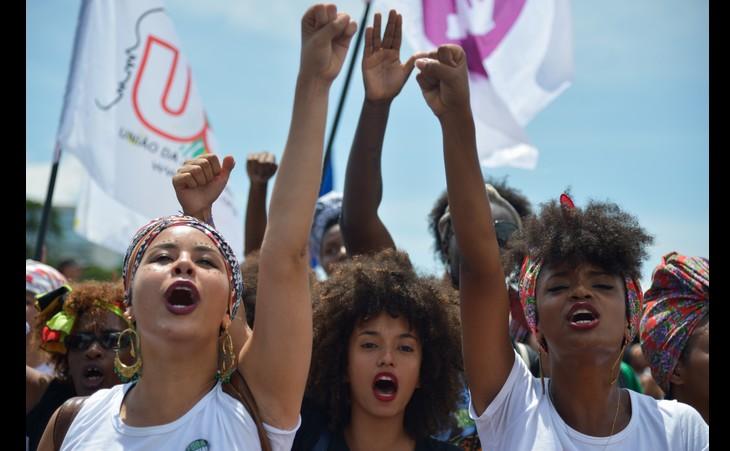 Mulheres negras de punhos levantados em marcha contra o racismo