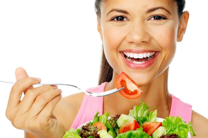 mulher comendo salada e sorrindo