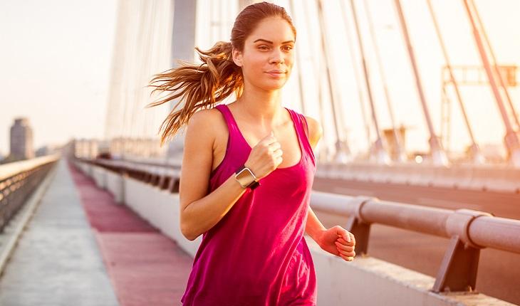 A foto mostra uma mulher com uma regata rosa correndo em uma ponte. Praticar exercícios físicos ajuda a turbinar as memórias