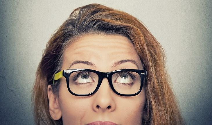 A foto mostra uma mulher de óculos olhando para cima