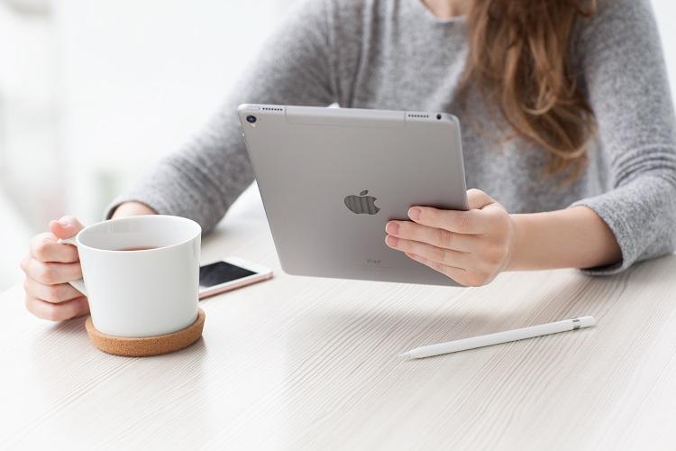 mulher sentada segurando tablet ipad iphone em cima da mesa sistema iOS