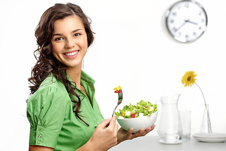 mulher sorrindo com pote de salada nas mãos