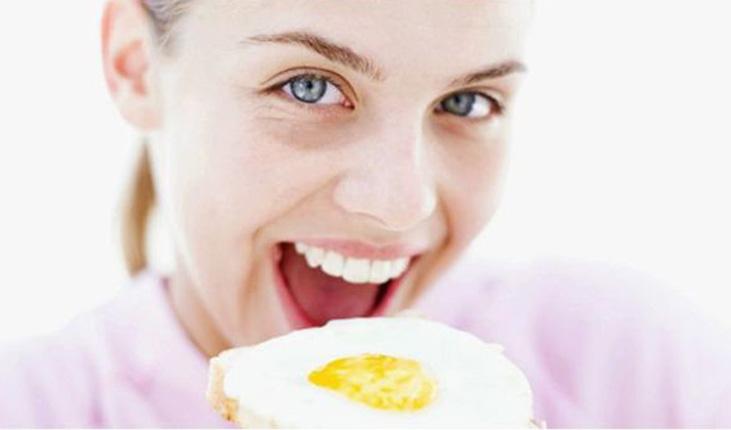 Mulher comendo um ovo frito