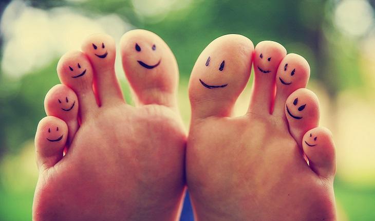 A foto mostra dois pés com carinhas felizes desenhadas em seus dedos. Recordar boas lembranças ajuda a melhorar as memórias