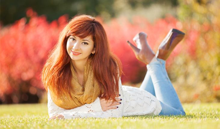 mulher de cabelo vermelho posando deitada na grama