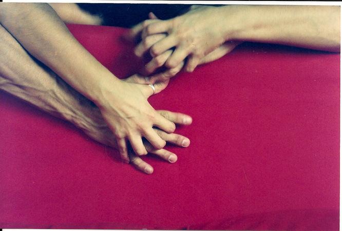 Casal de mãos entrelaçadas sobre uma superfície vermelha ponto g