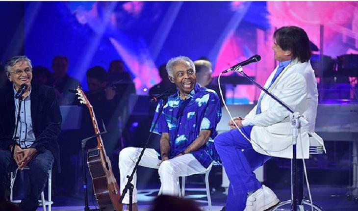 Imagem com cena do Programa Especial de Final de Ano com Roberto Carlos, Caetano Veloso e Gilberto Gil no palco