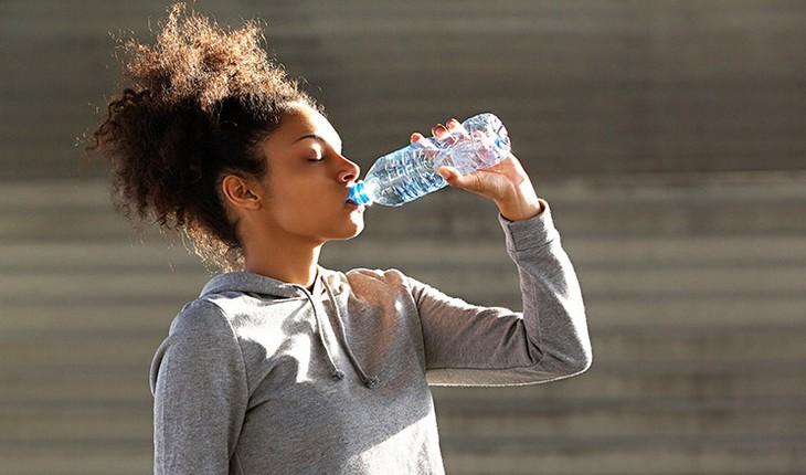 mulher bebendo água com trajes de corrida