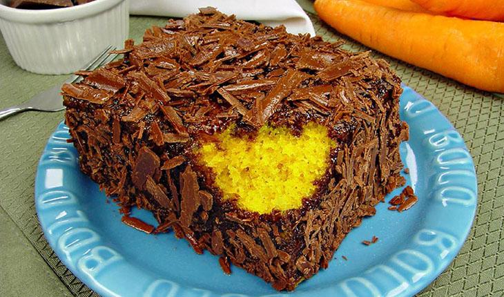 bolo de cenoura com raspas de chocolate com uma modida em um dos cantos e sobre em um prato azul