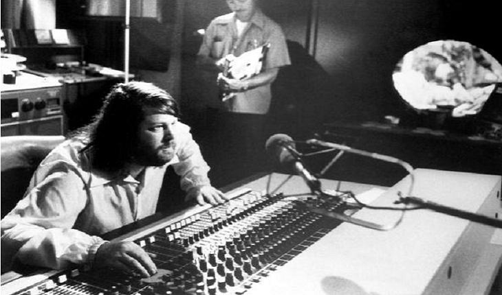 O cantor e compositor Brian Wilson atrás de uma mesa de som compondo, foto em preto e branco