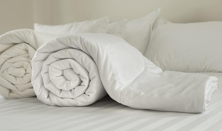 A foto mostra uma cama com edredons dobrados.