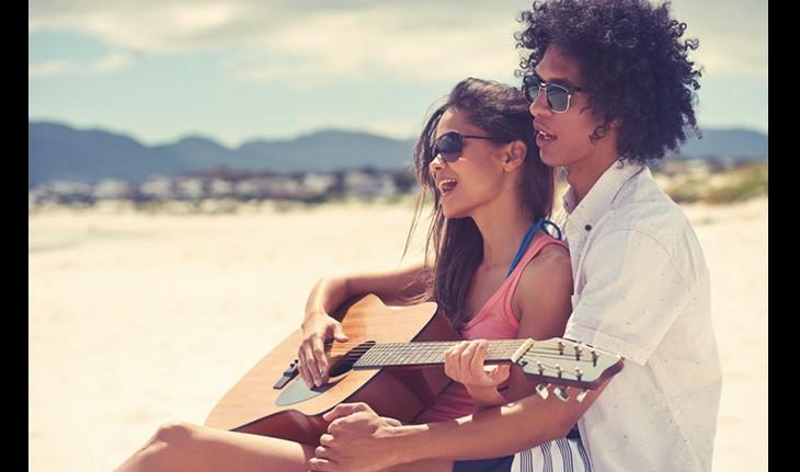 casal na praia cantando e tocando violão