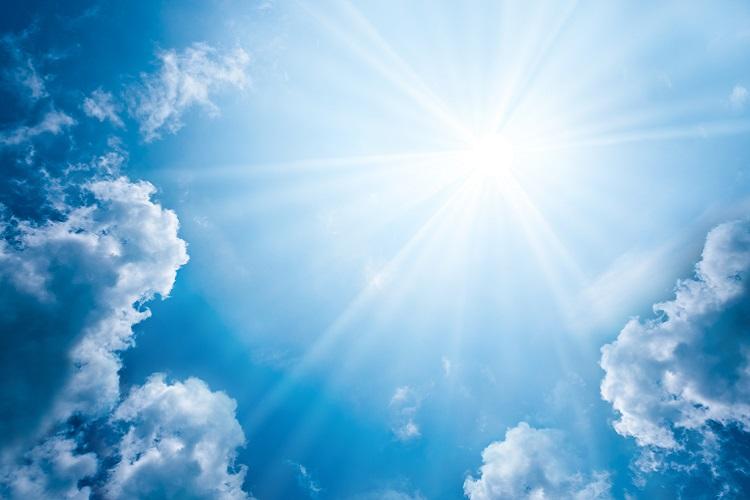 A imagem mostra um céu com vários tons de azul, nuvens e a luz do sol
