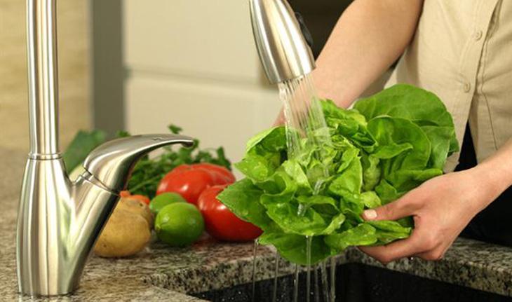 mulher lavando verduras na pia da cozinha